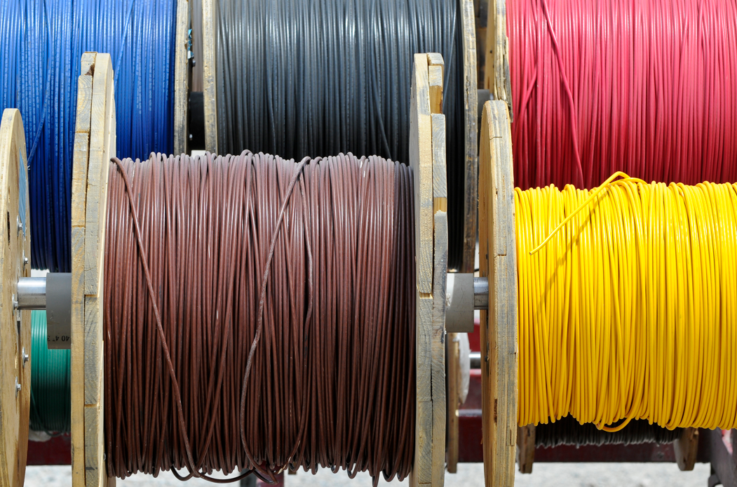 Bulk spools of colored copper and aluminum electrical wire, including yellow, red, brown, black, and blue options, ready for commercial distribution.