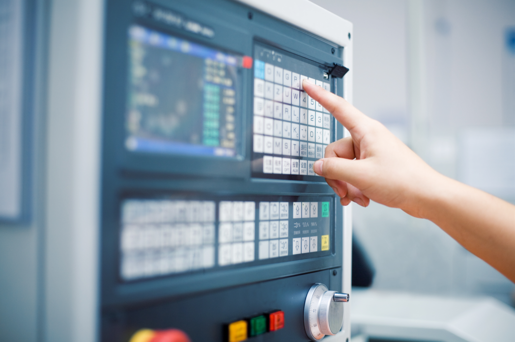Close-up of hand operating industrial control panel, illustrating automation integration with lighting and switchgear systems.
